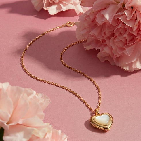 Gold necklace with a heart-shaped pendant on pink flowers