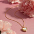 Gold necklace with a heart-shaped pendant on pink flowers