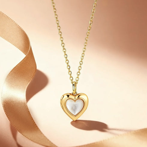 Gold heart-shaped pendant necklace with a white stone on a soft pink background